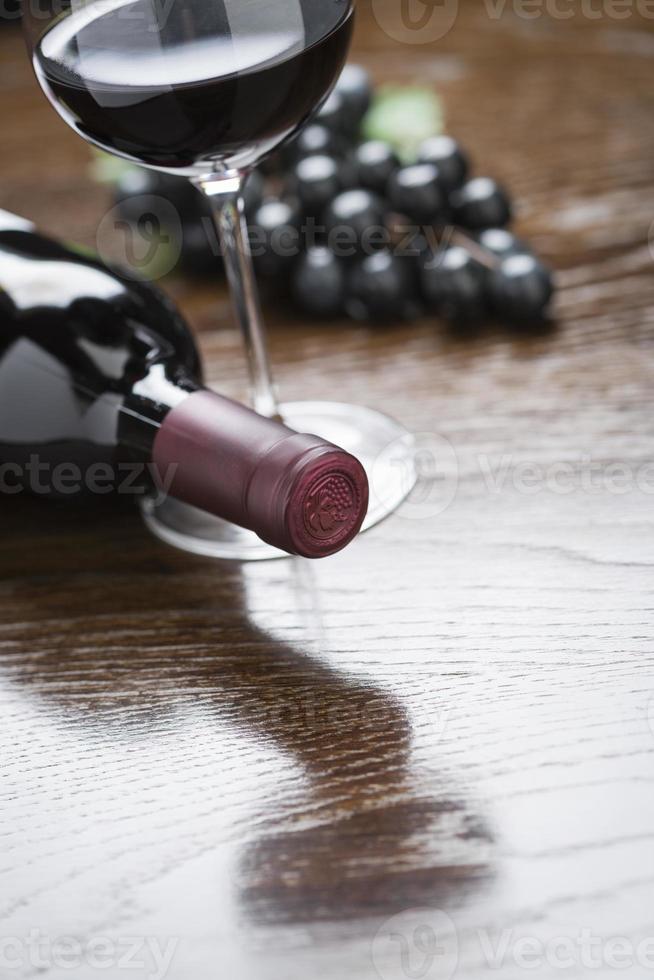 Abstract Wine Bottle, Glass and Grapes on Reflective Wood Surface photo