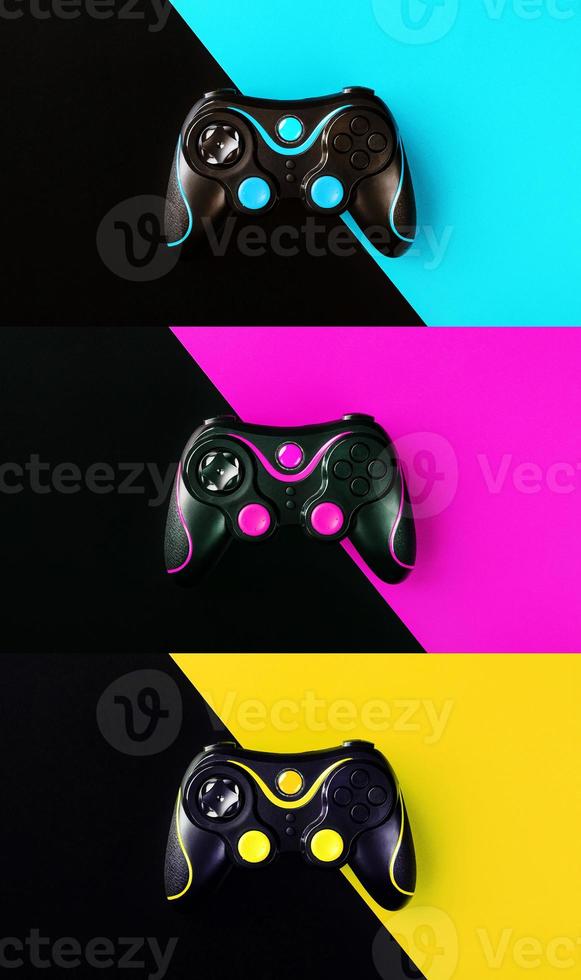 Three gaming joysticks, on yellow-cyan-Magenta and black background. photo