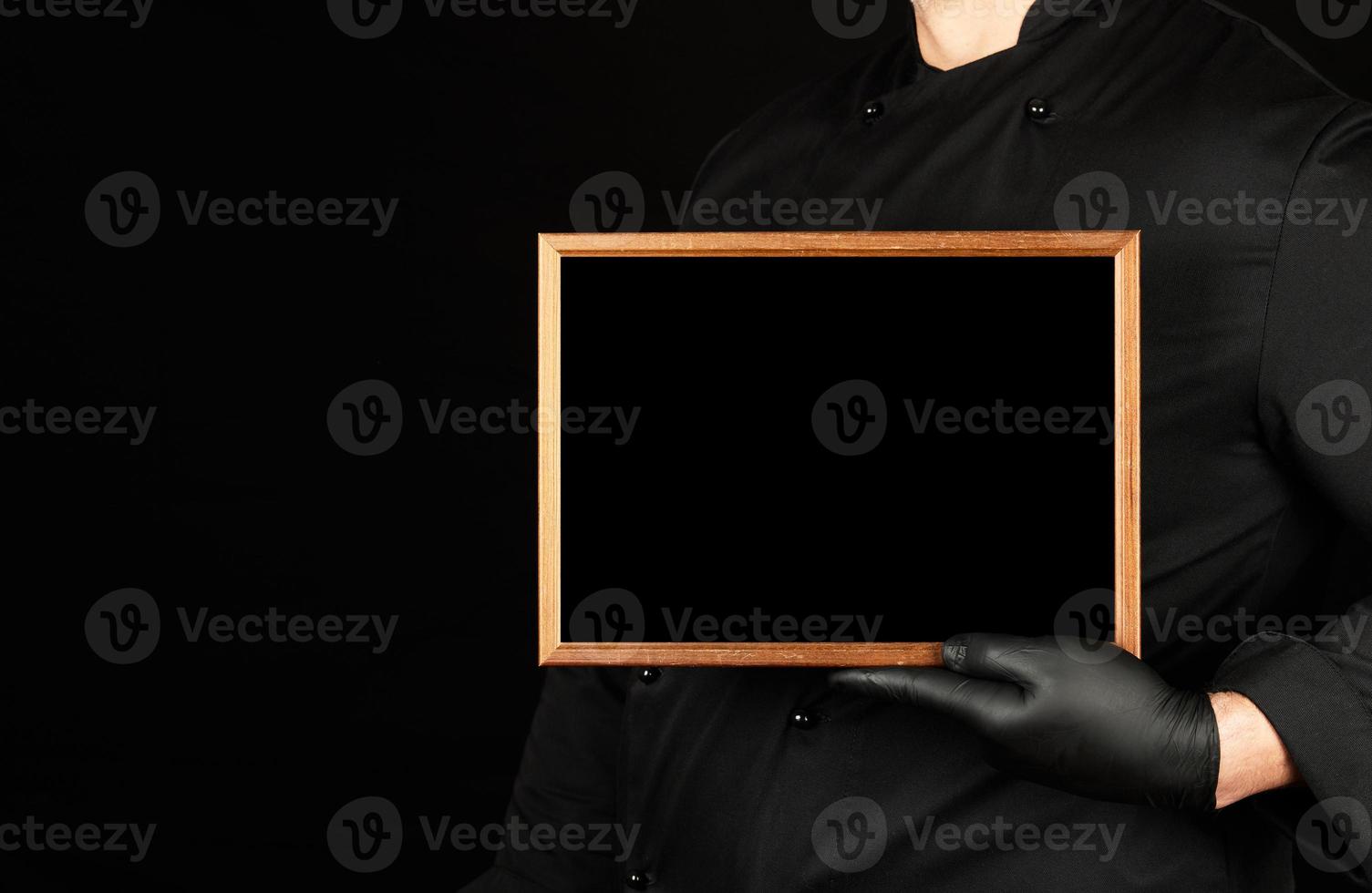 chef in black uniform and black latex gloves holds an empty wooden frame photo