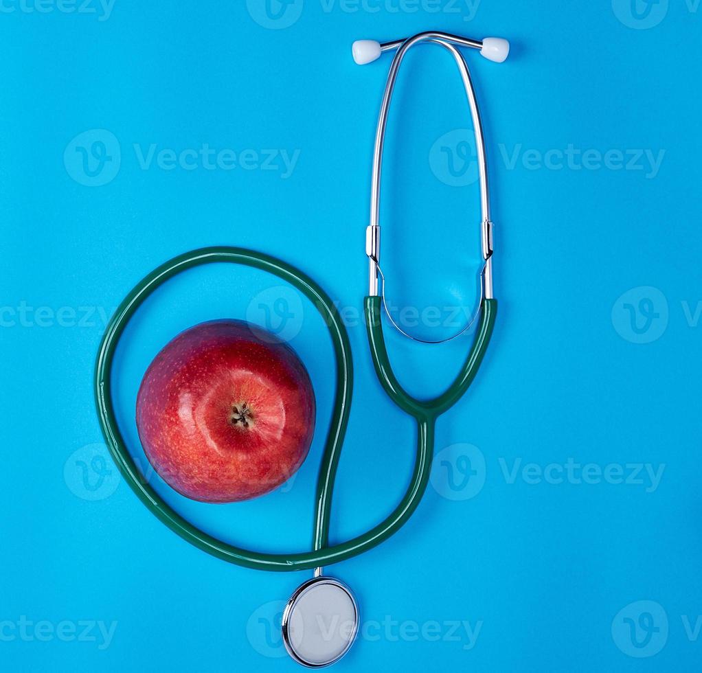 green medical stethoscope and ripe red apple photo