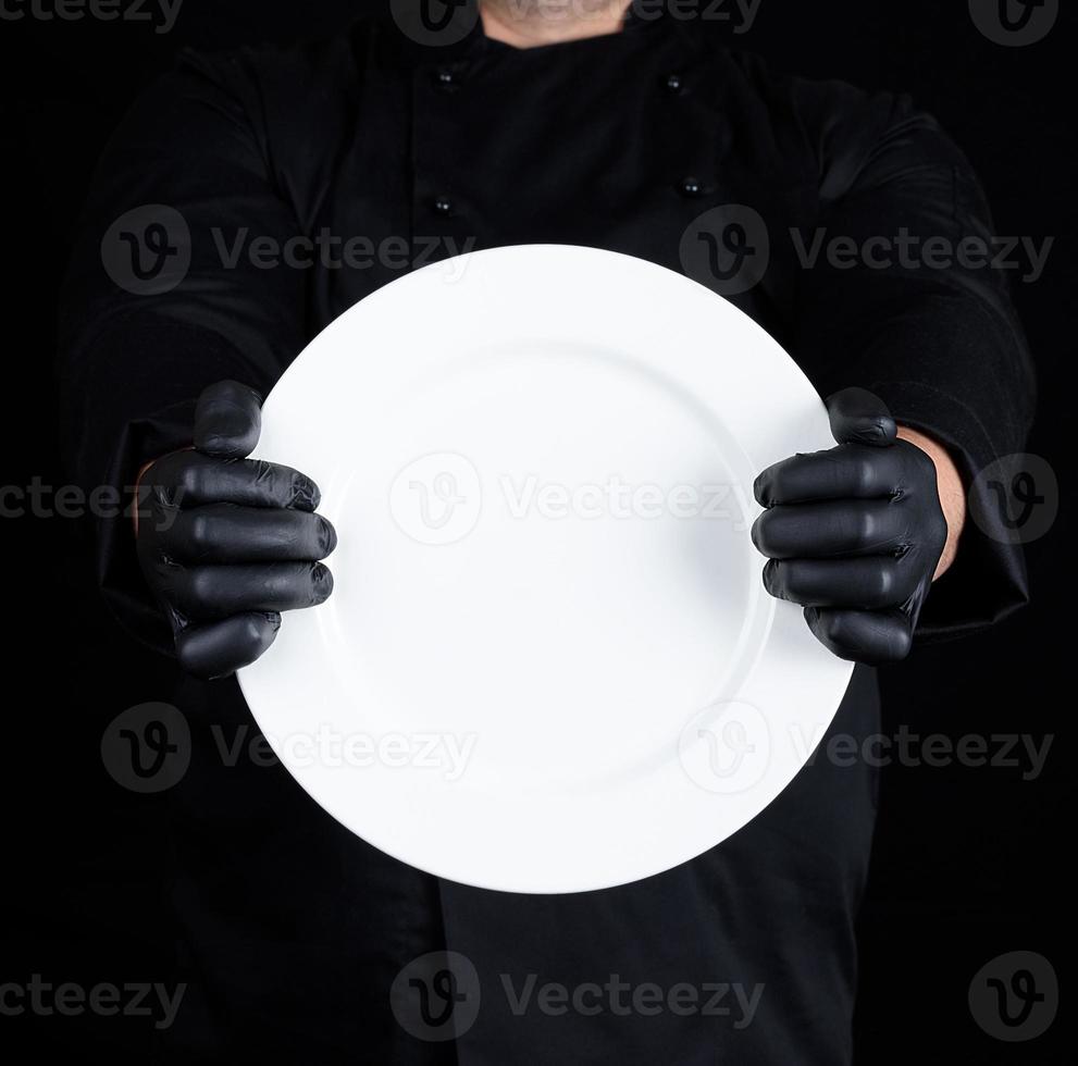 Chef in black uniform  holding a round empty plate photo