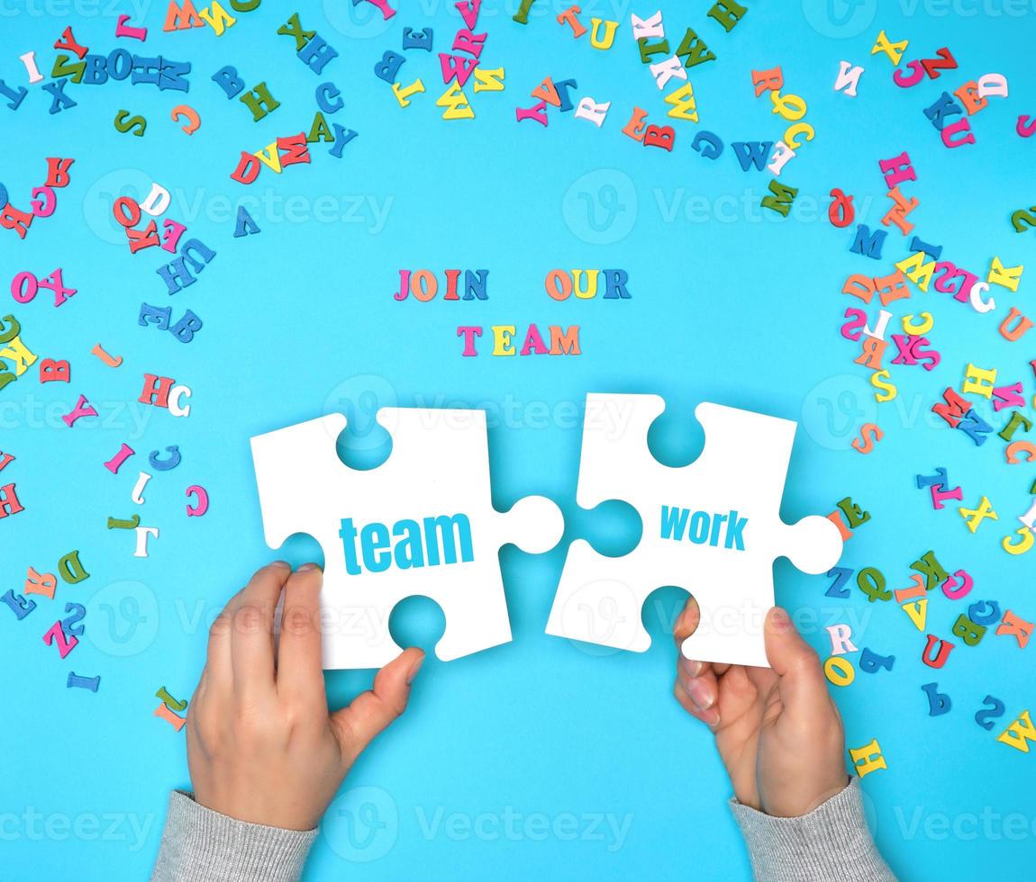 women hand hold  large white puzzles and the inscription join our team photo