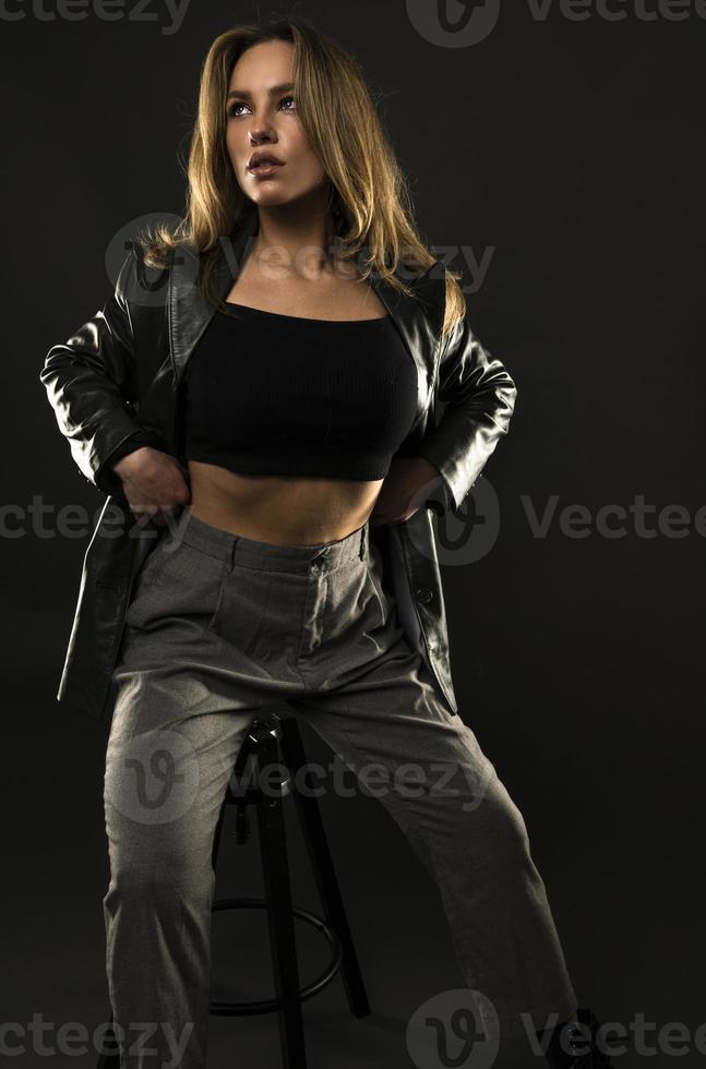 beautiful American woman posing on black background wearing black leather jacket. Fashion model wearing leather pants and jacket Fashion model wearing leather Jacket photo