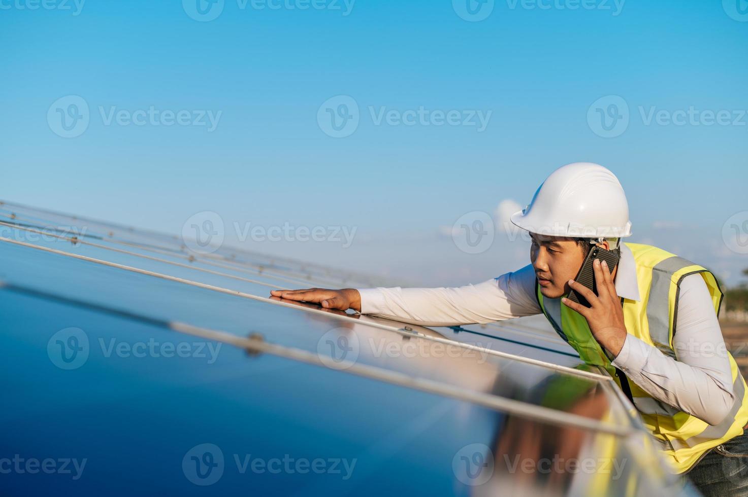 joven ingeniero usa un teléfono inteligente mientras trabaja en una granja solar foto