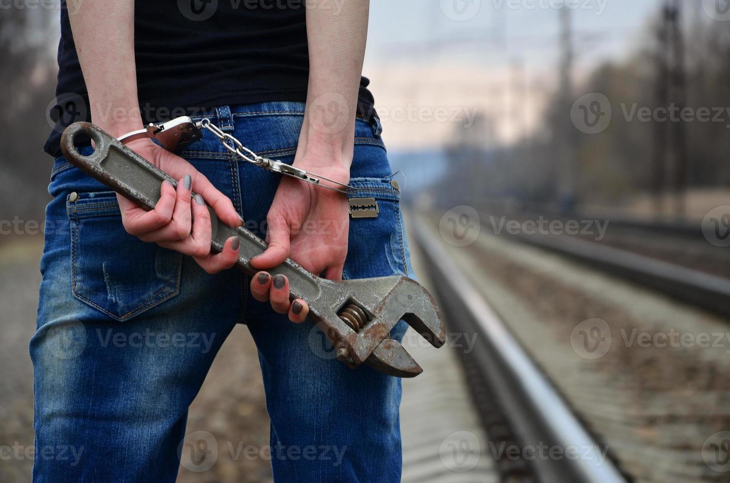 la chica esposada con la llave ajustable en el ferrocarril foto