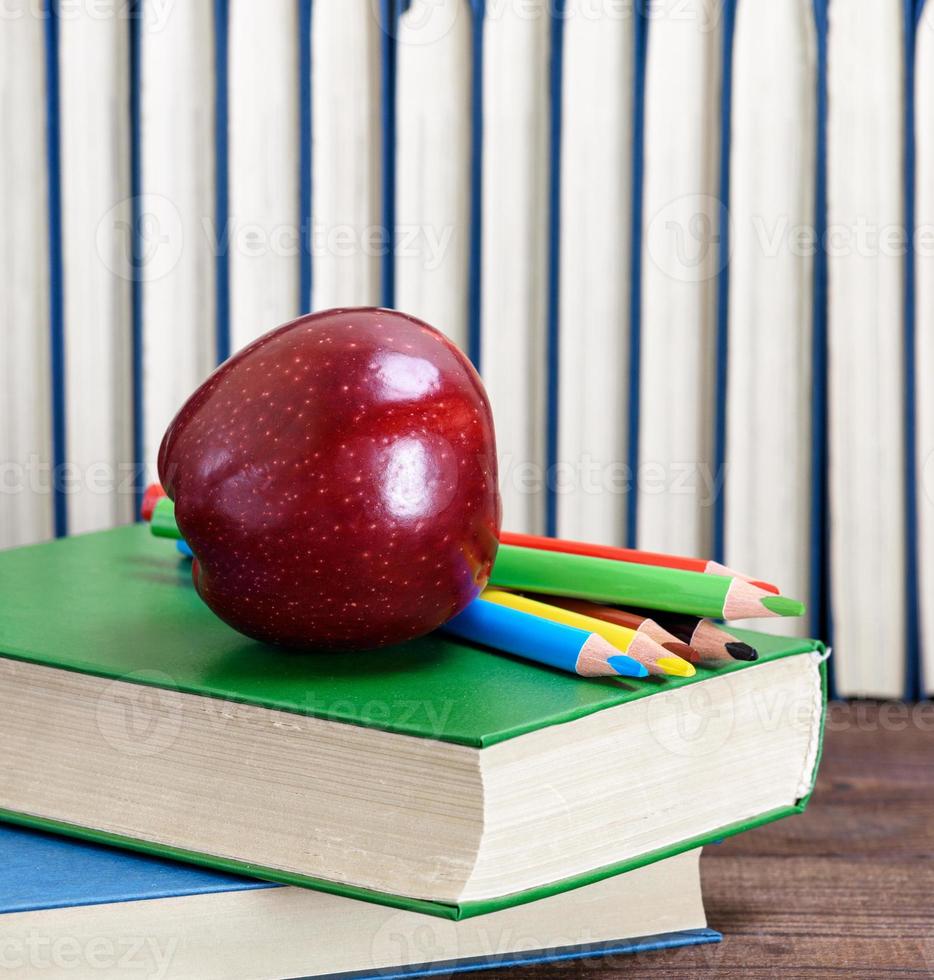 ripe red apple lying on a stack of books photo