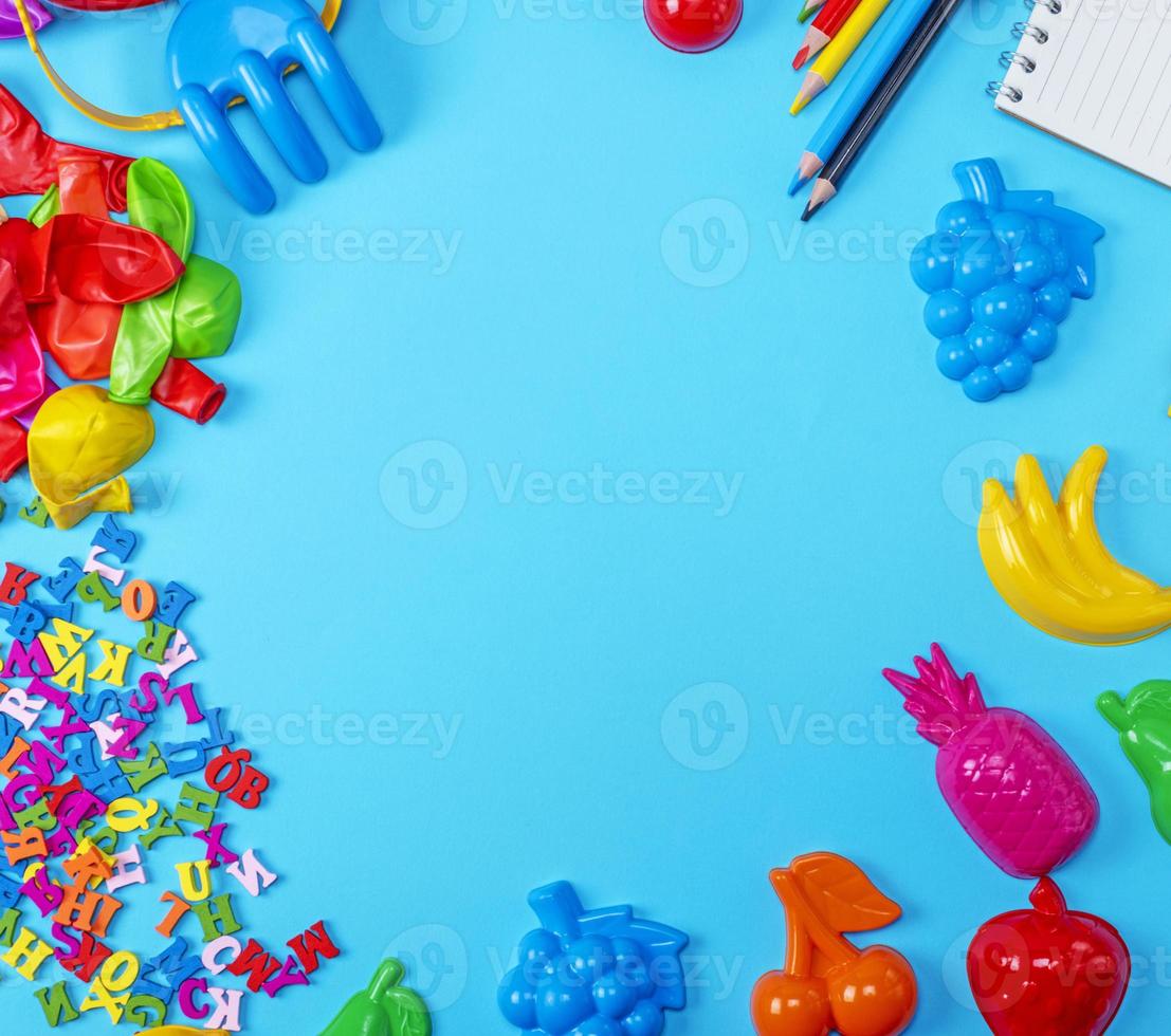 Blue background with childrens plastic toys, pencils, balloons and wooden letters photo