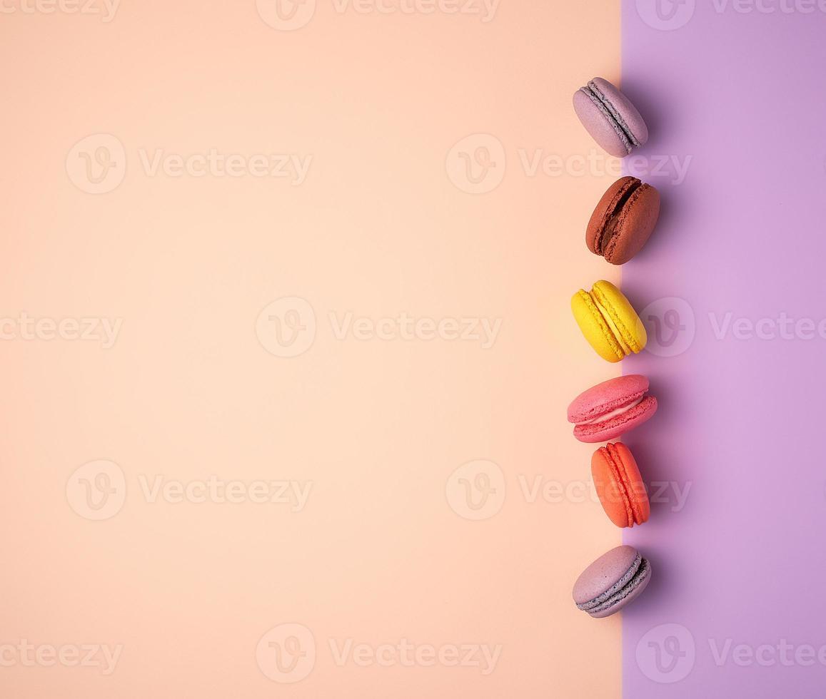 multi-colored macarons with cream on a purple-beige background, flat lay photo