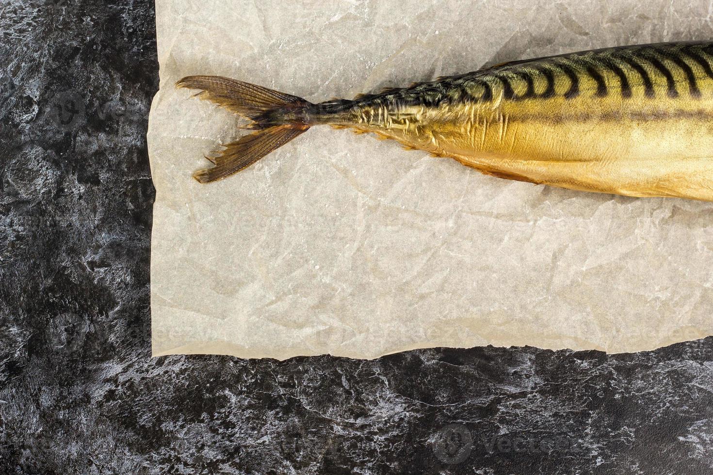 Smoked mackerel without head on baking paper on black background. copyspace top view photo