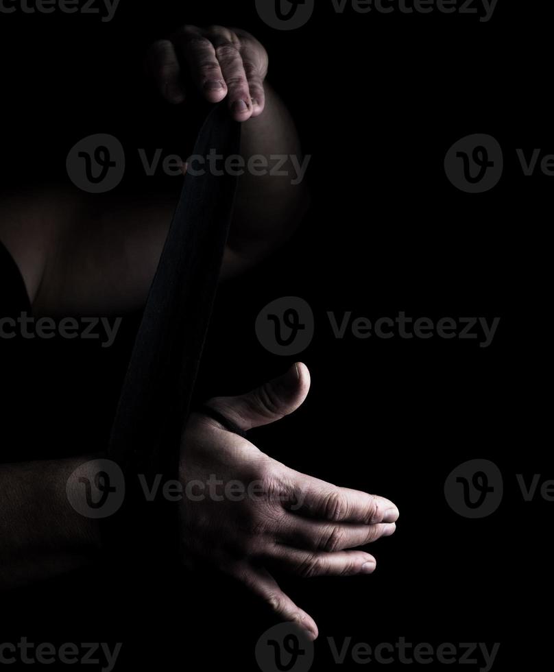 man wraps his hands in black textile bandage for sports photo