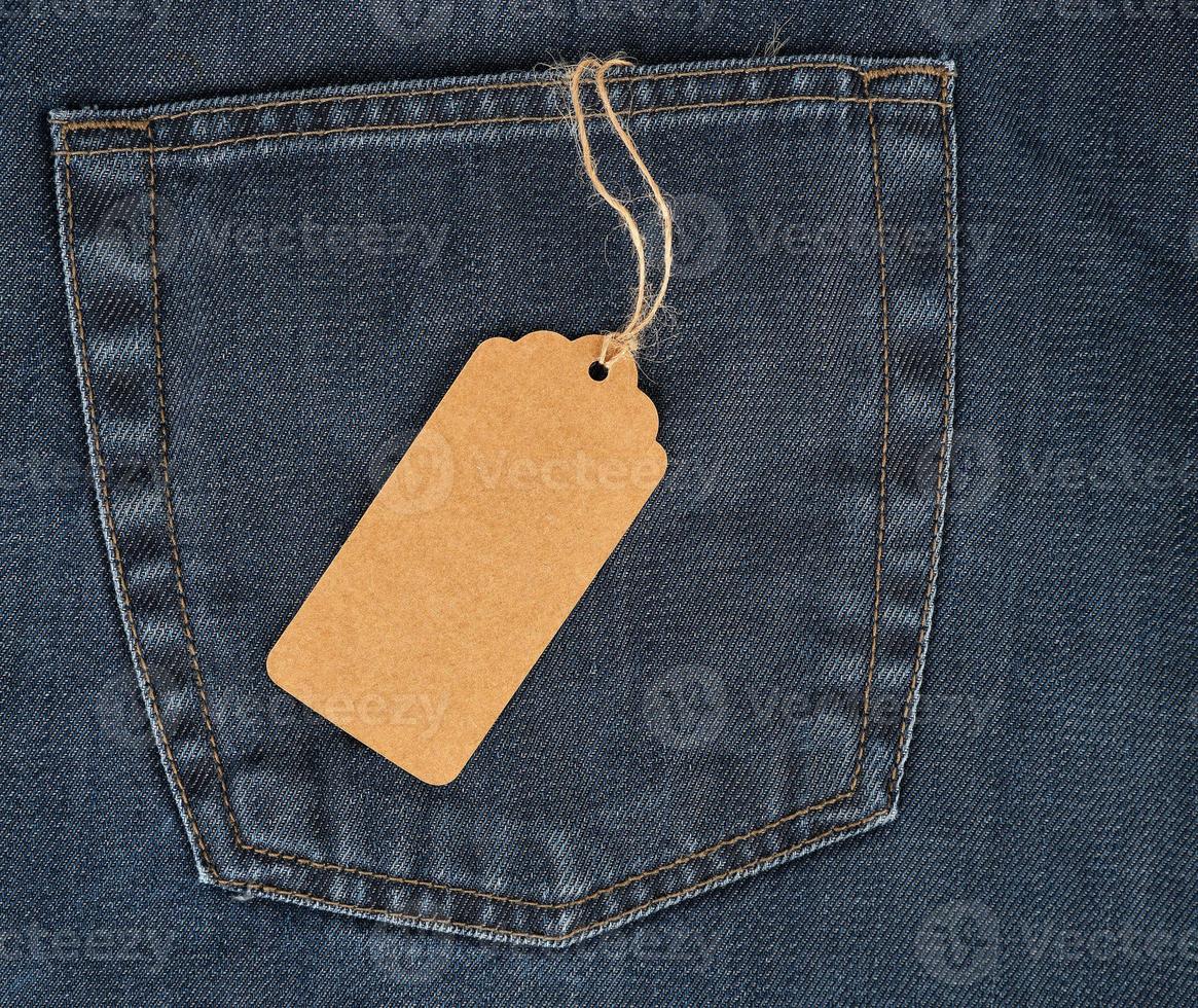 tied on a rope is an empty rectangular brown paper tag on blue jeans photo