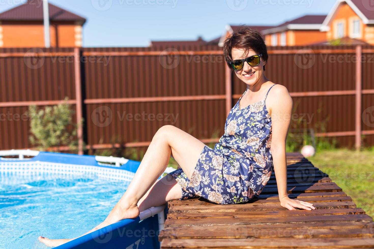 retrato de una mujer joven y guapa en pijama sentada cerca de una piscina inflable - concepto de vida de verano y campo foto