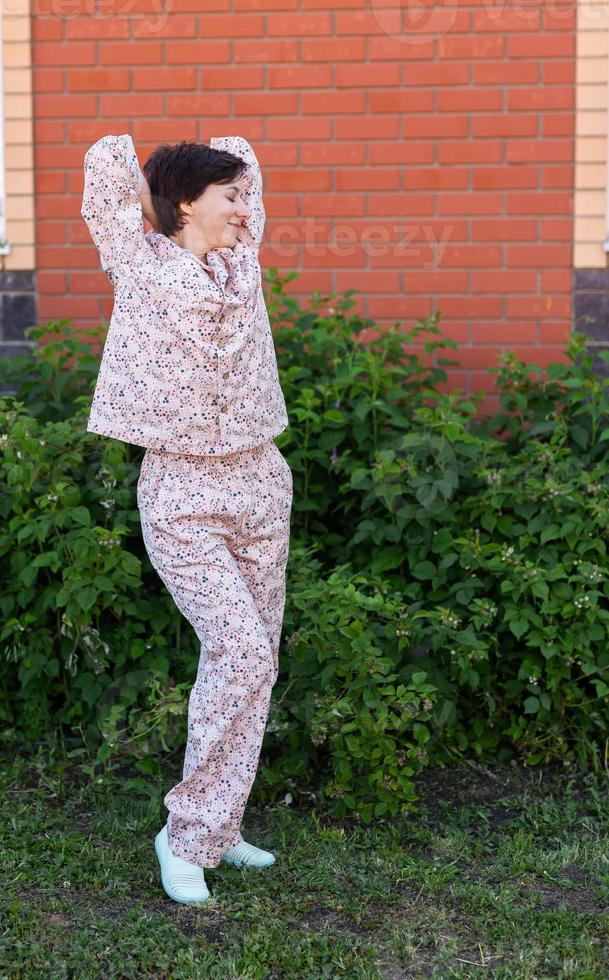 Cheerful woman in home wear pajama outdoor brick wall backyard background emotions - sleepwear and homewear concept photo