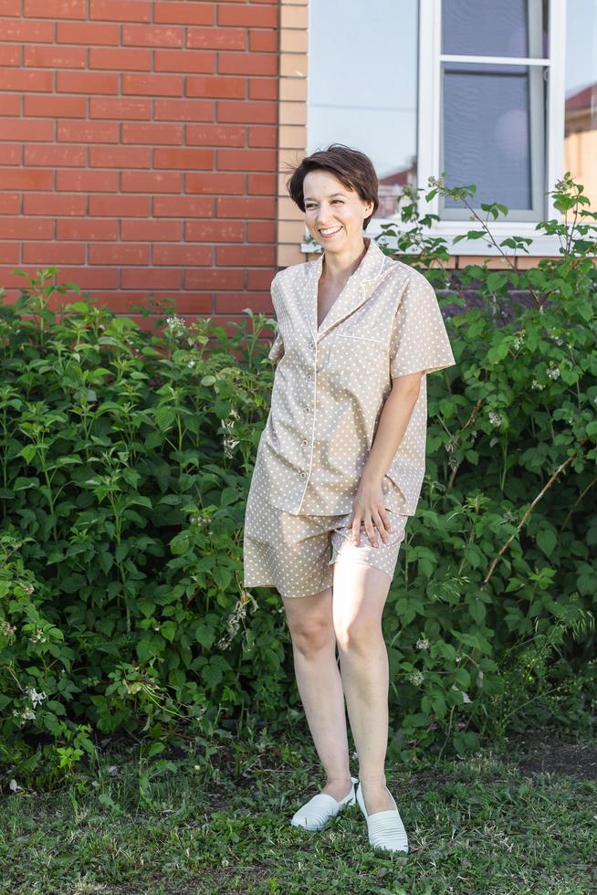 mujer alegre en casa usar pijama exterior pared de ladrillo emociones de fondo del patio trasero - ropa de dormir y concepto de ropa de casa foto