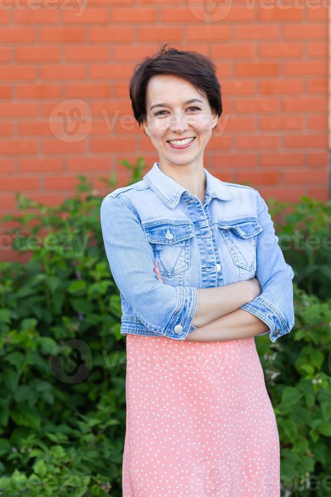 Cheerful young woman wearing stylish dress in patio. Happy smiling girl making having fun outdoor. Happy beautiful woman enjoying summer photo