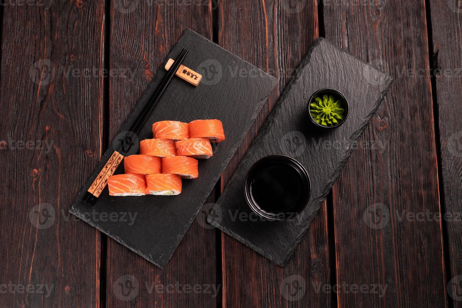 Sushi roll philadelphia with salmon and cucumber and cream cheese on black background. Sushi menu. Japanese food concept top view photo