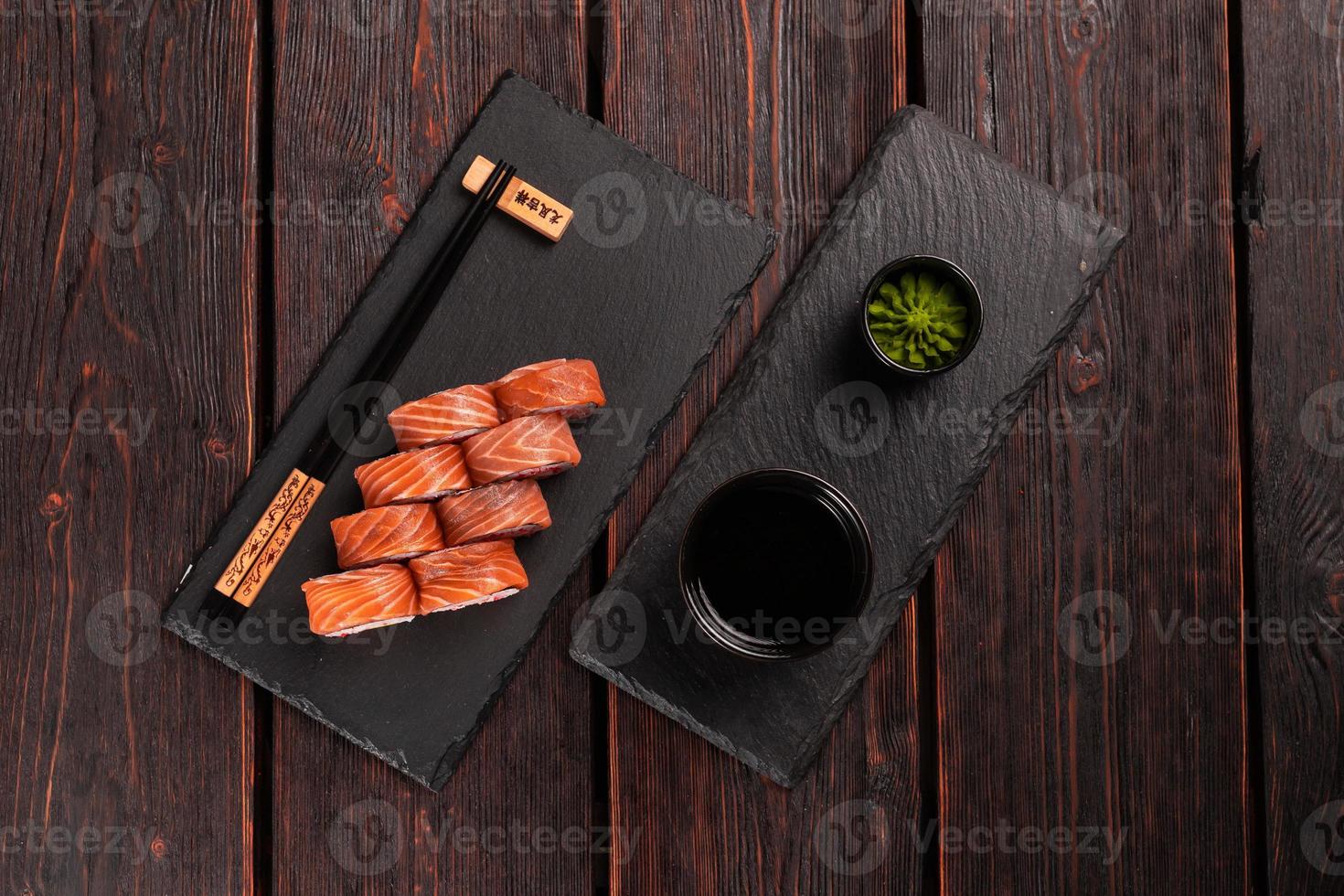 Sushi roll philadelphia with salmon and avocado and cream cheese, caviar on black background top view. Sushi menu. Japanese food concept photo