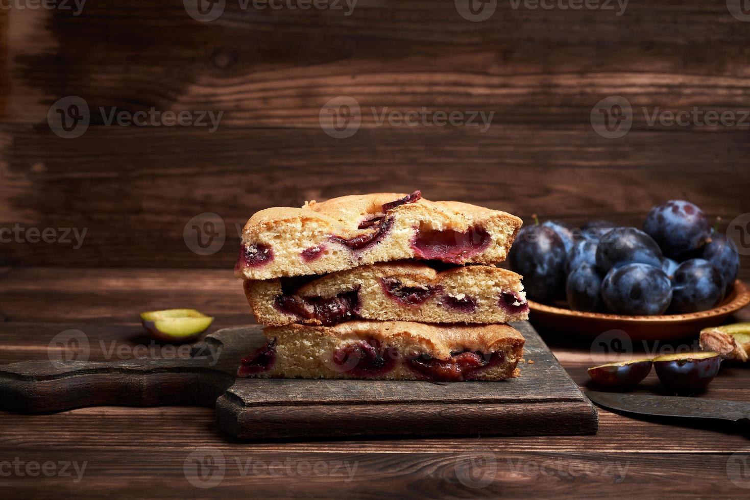 stack of triangular slices of sponge cake with blue plums photo