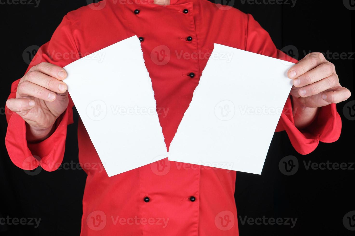 man in a red uniform holds a white sheet of paper torn in half photo