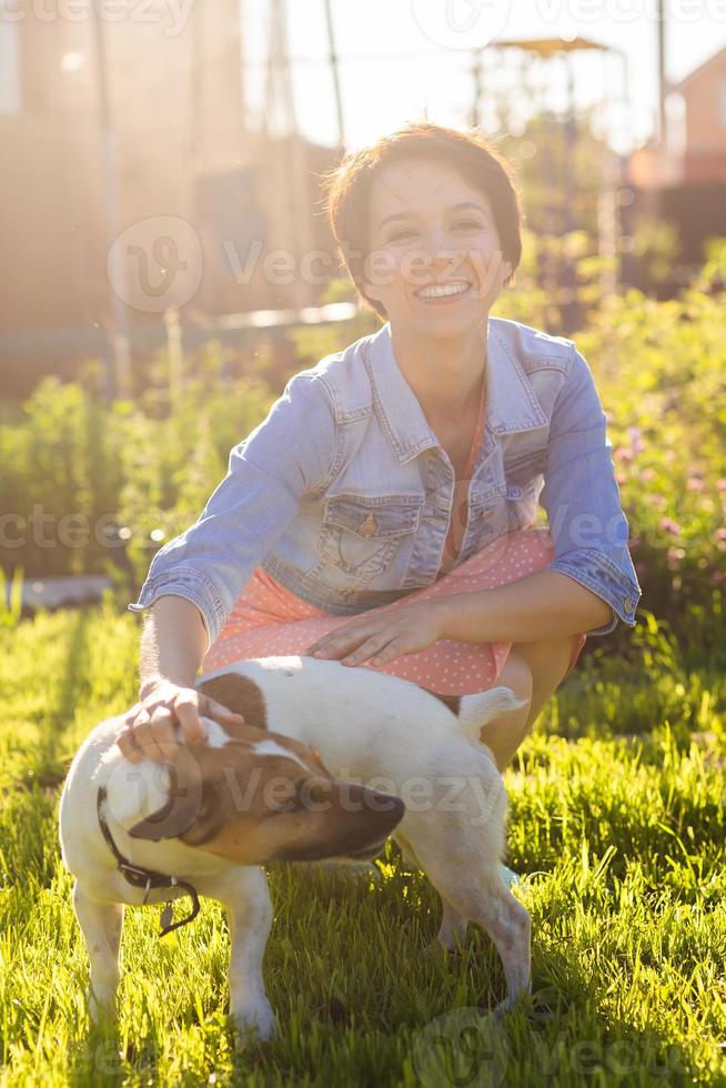 Young woman plays with her dog on the grass on backyard. The concept of animals and friendship or pet owner and love photo