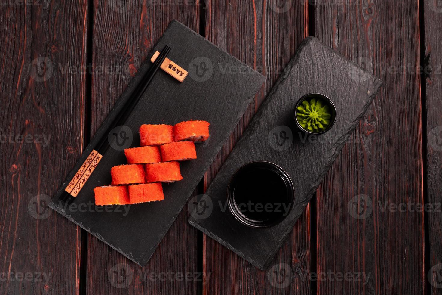 California sushi roll with crab, avocado, cucumber and tobiko caviar served on black board top view - Japanese food photo