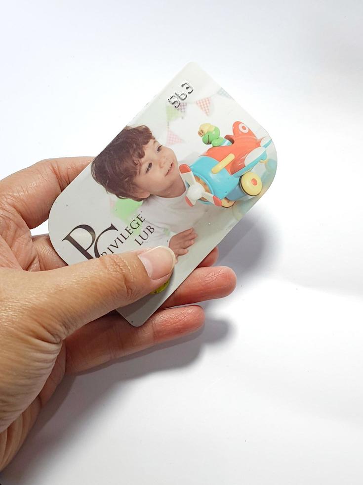 West Java, Indonesia on July 2022. Isolated photo of a hand holding a loyalty card, Mothercare ID Priviledge Card.