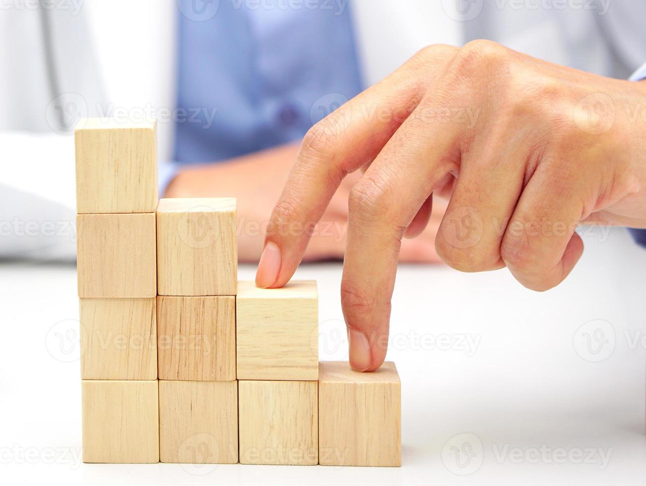 Two fingers of doctor is walking up stairs wooden blocks. Concept of Success, progress and growth. photo