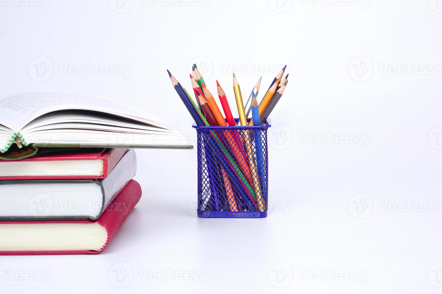 Stack of books with open book and colorful pencils on white background. Knowledge and education concept. photo