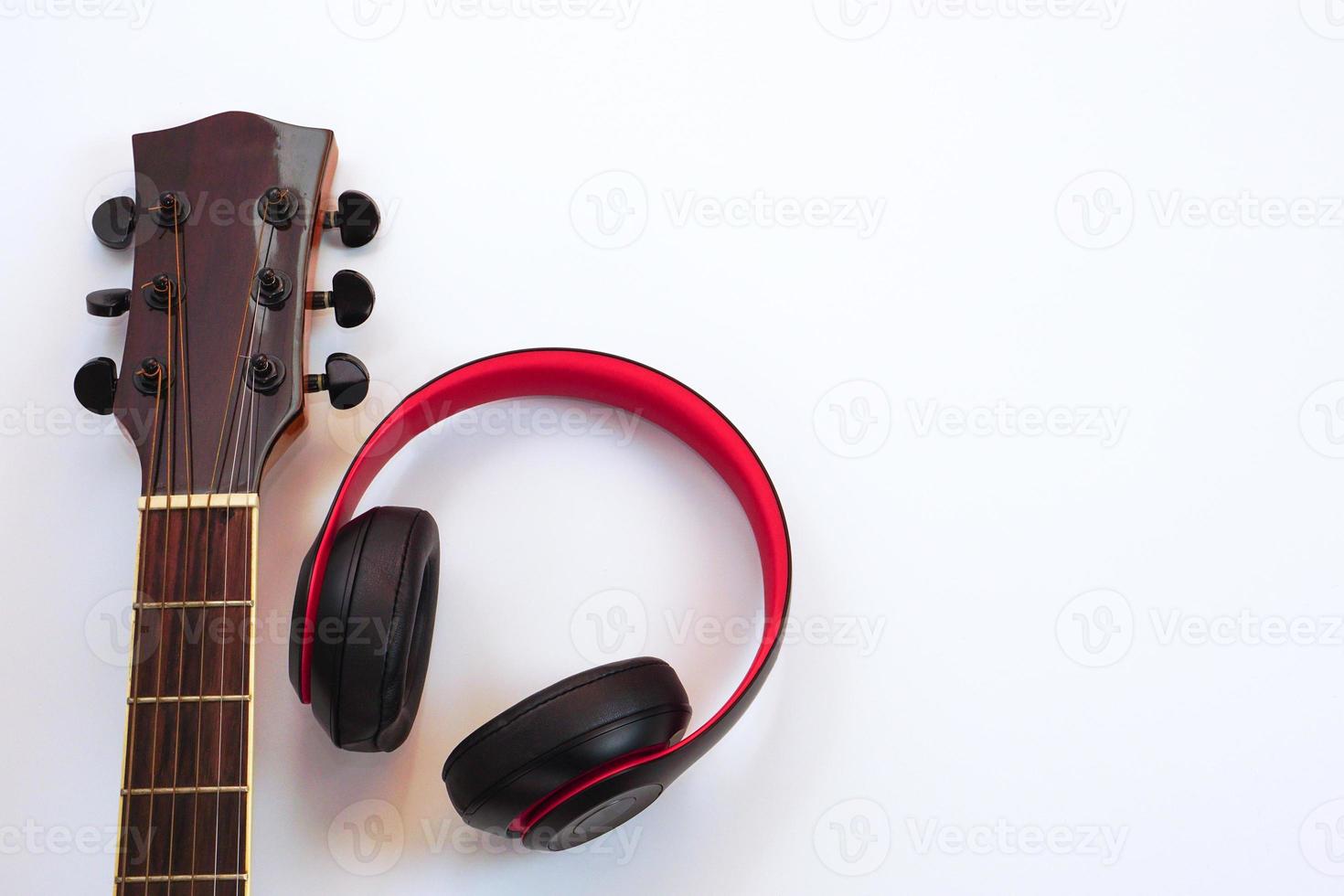 Acoustic guitar on a white background and the headphones are placed on the side. Concept of love, leisure and music. photo