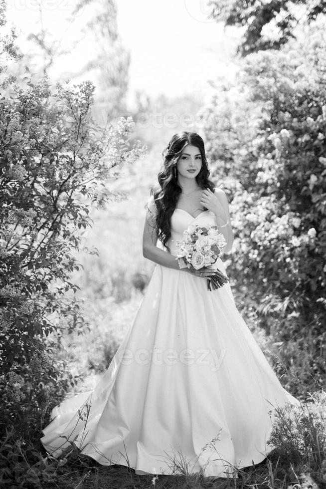 young girl bride in a white dress in a spring forest in lilac bushes photo