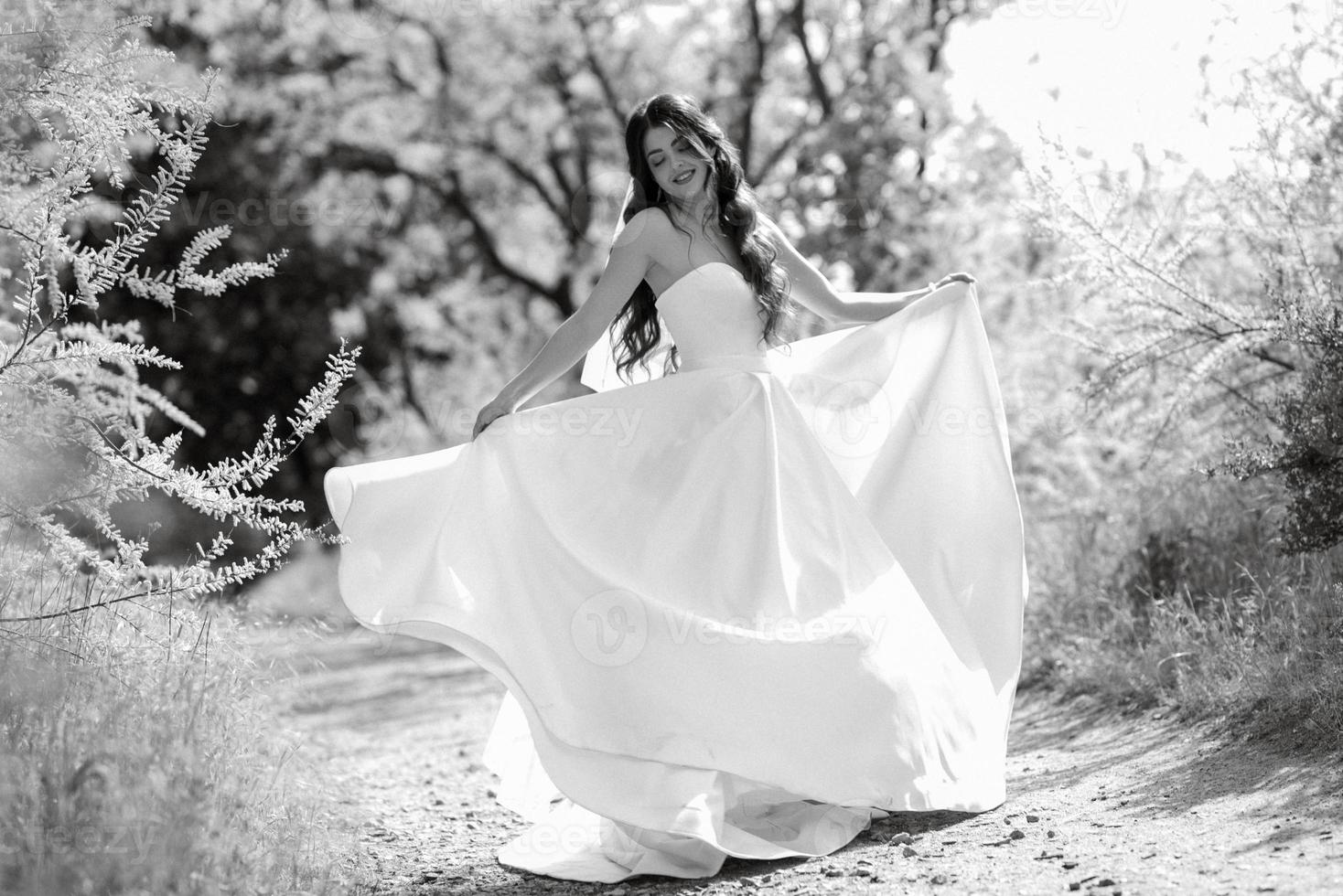 a young girl bride in a white dress is spinning on a path photo