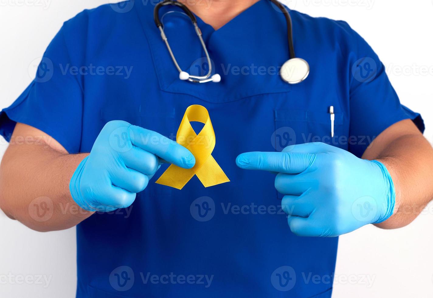 doctor in a blue uniform and sterile latex gloves holds a yellow ribbon in his hand photo