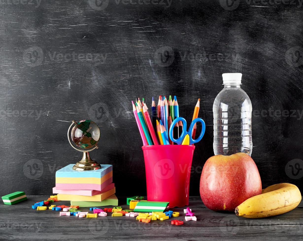 manzana, plátano, botella de agua y papelería para la escuela foto