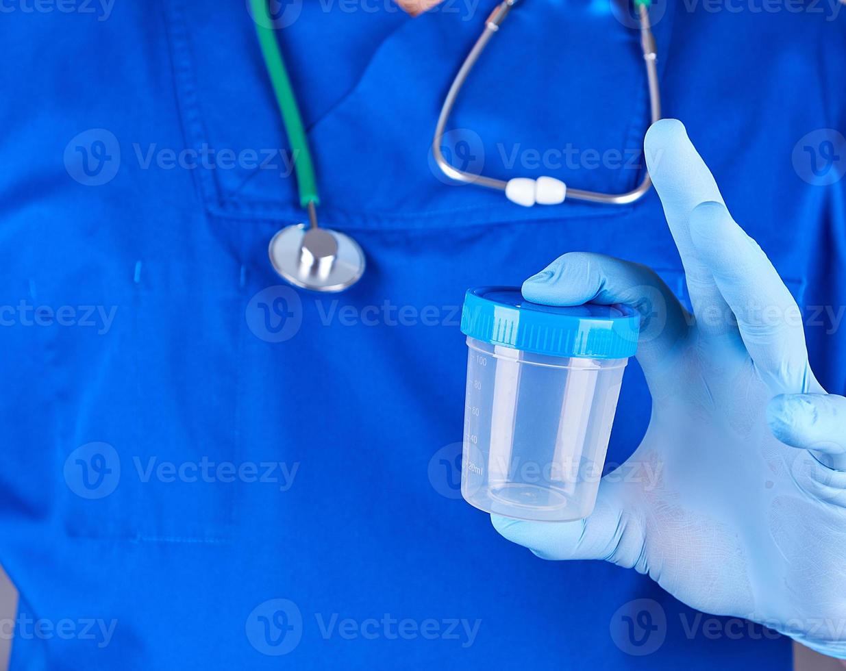 the doctor in blue uniform and latex gloves is holding an empty plastic