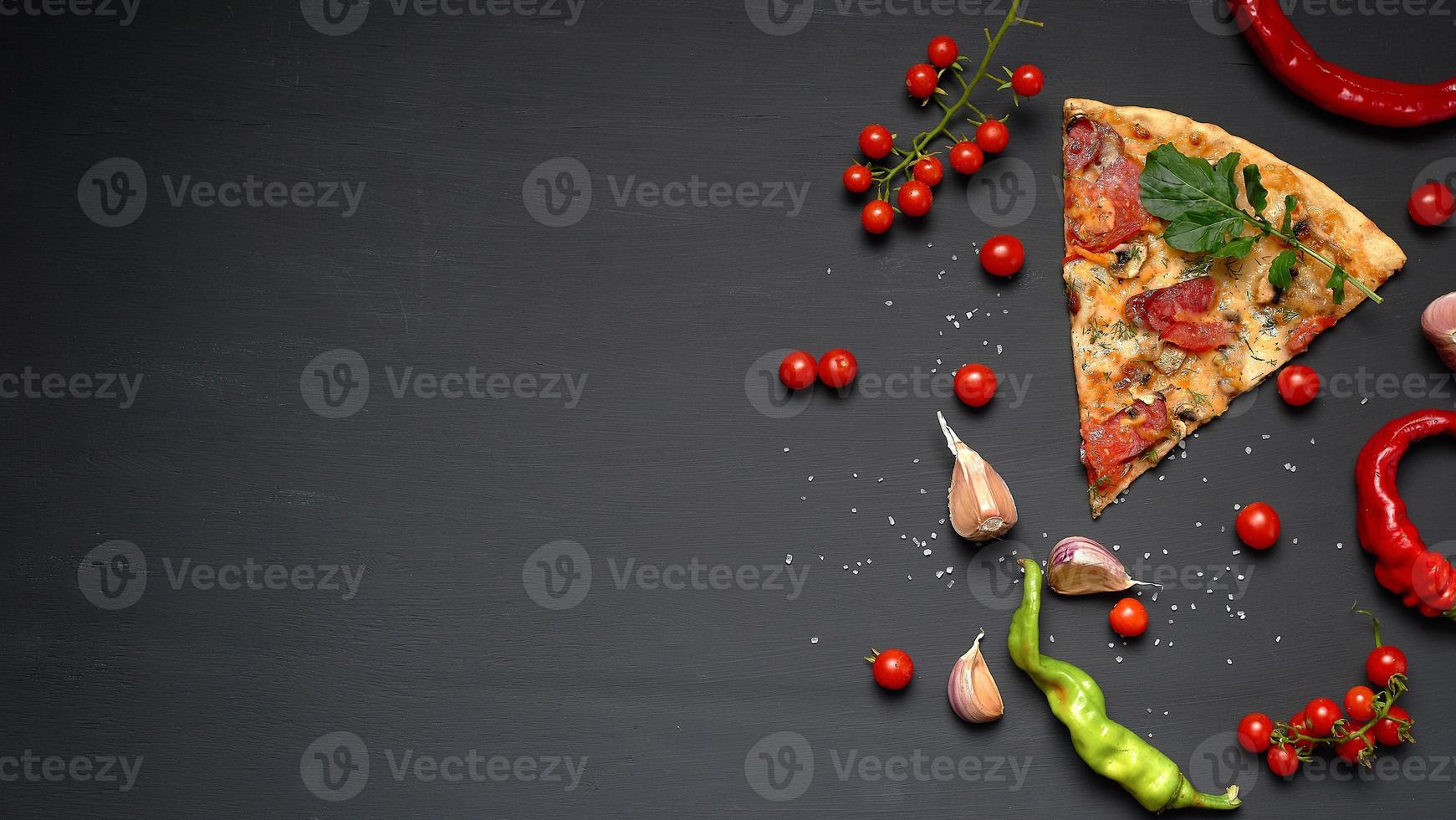 triangular piece of baked pizza with mushrooms, smoked sausages, tomatoes and cheese photo