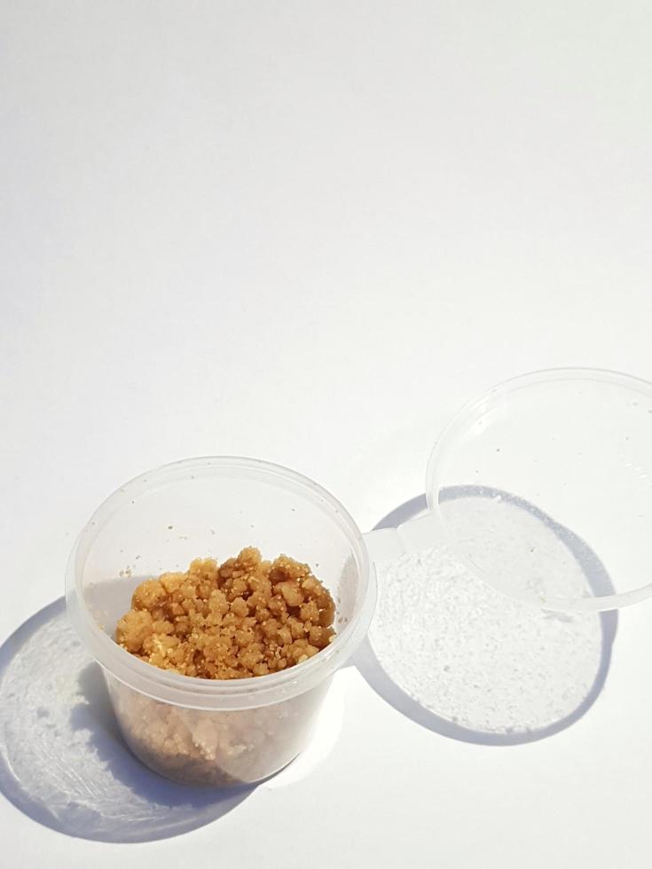 This is a plastic container in the shape of a small, transparent tube filled with crumbs of biscuits. photo