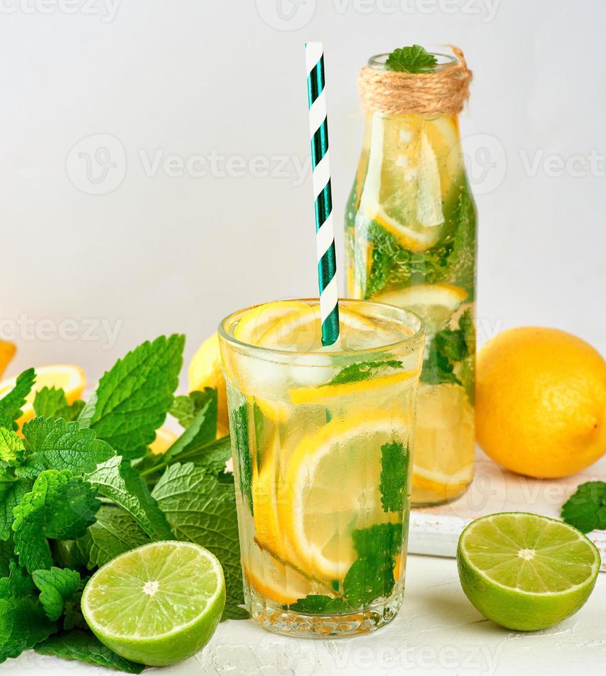 summer refreshing drink lemonade with lemons, mint leaves, lime in a glass bottle photo