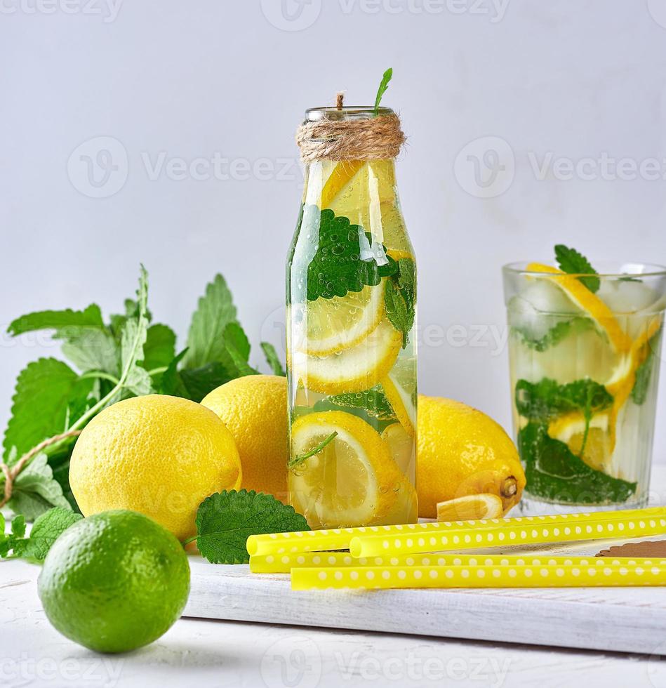summer refreshing drink lemonade with lemons, mint leaves, lime in a glass bottle photo
