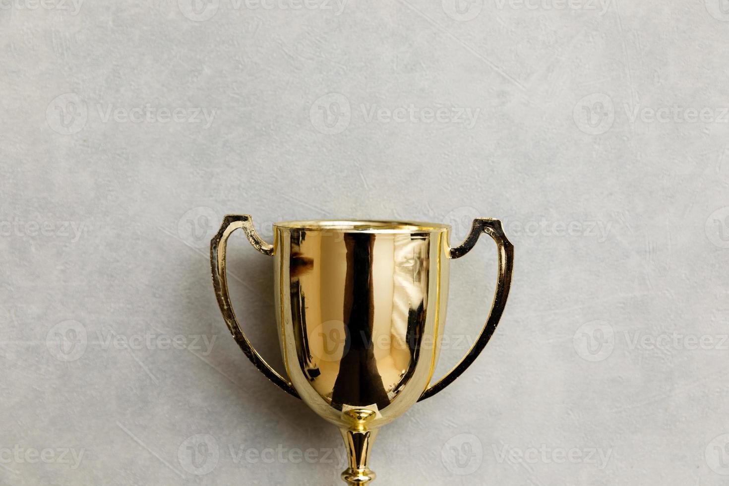 Simply flat lay design winner or champion gold trophy cup on concrete stone grey background. Victory first place of competition. Winning or success concept. Top view copy space. photo