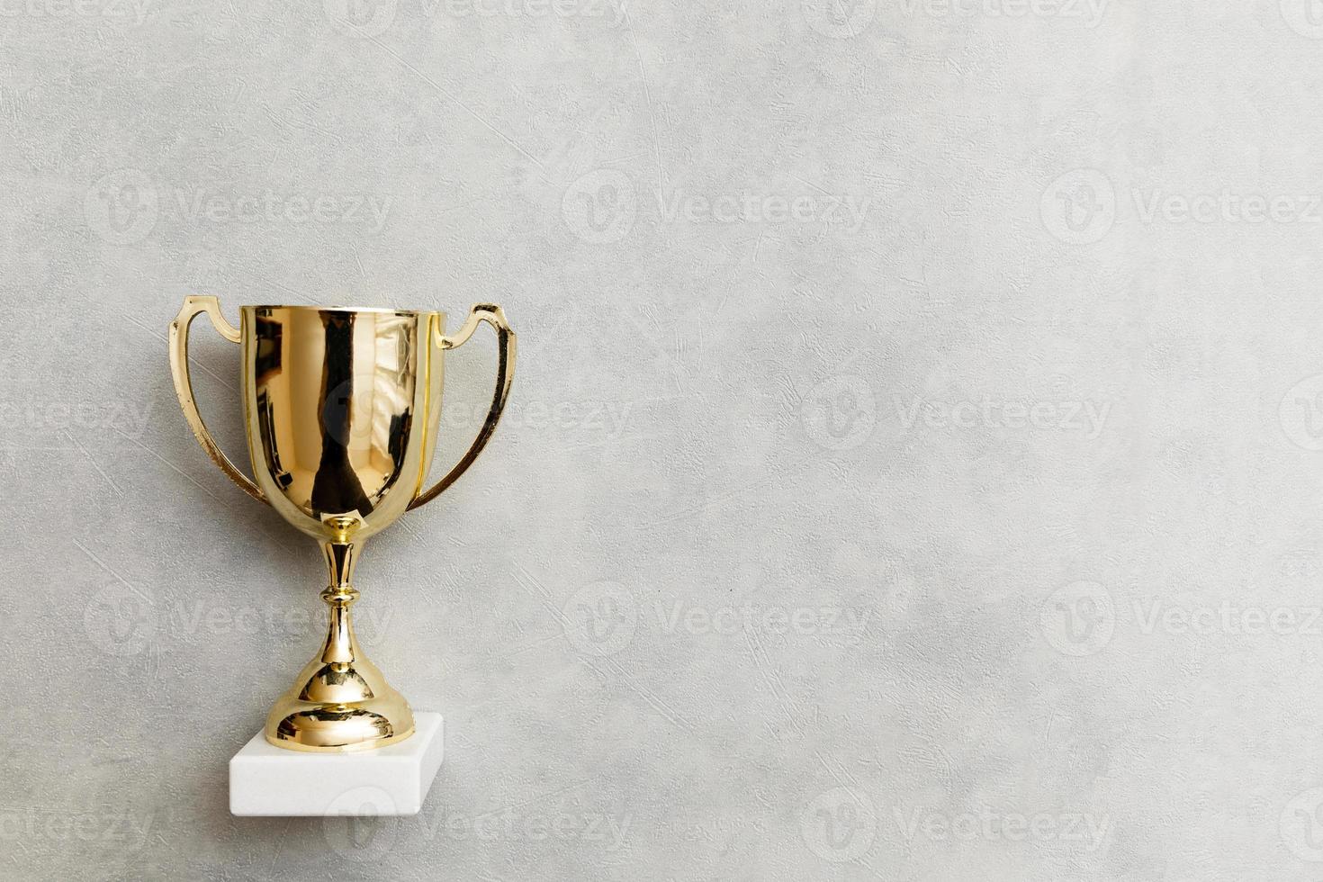 Simply flat lay design winner or champion gold trophy cup on concrete stone grey background. Victory first place of competition. Winning or success concept. Top view copy space. photo