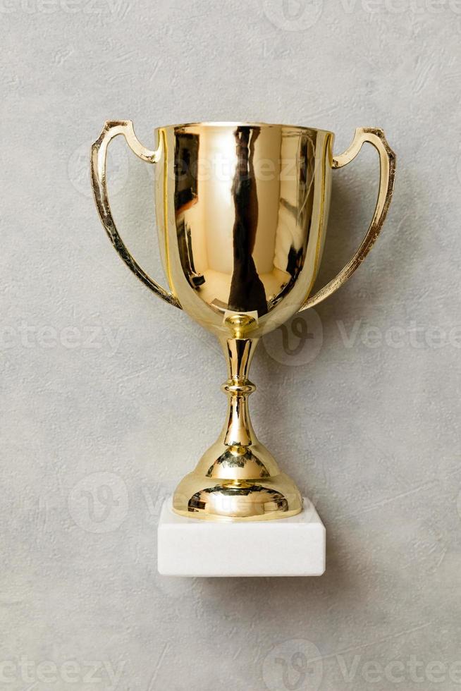 Simply flat lay design winner or champion gold trophy cup on concrete stone grey background. Victory first place of competition. Winning or success concept. Top view copy space. photo