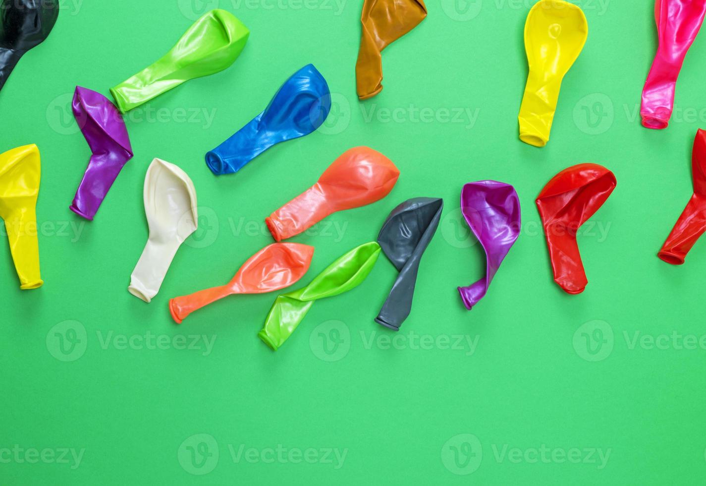 colorful deflated balloons on a green background photo