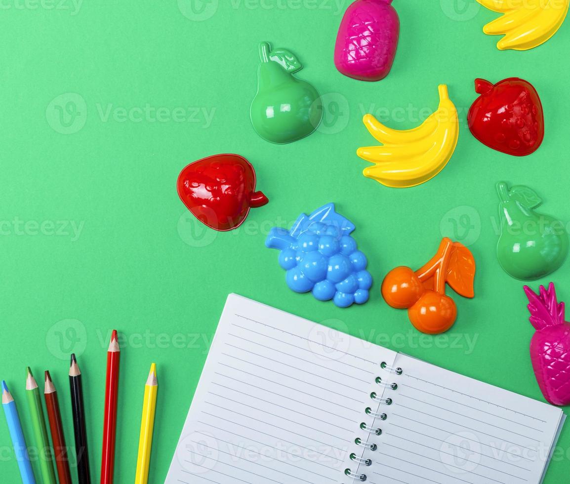 open notebook with empty white sheets and multicolored wooden pencils photo