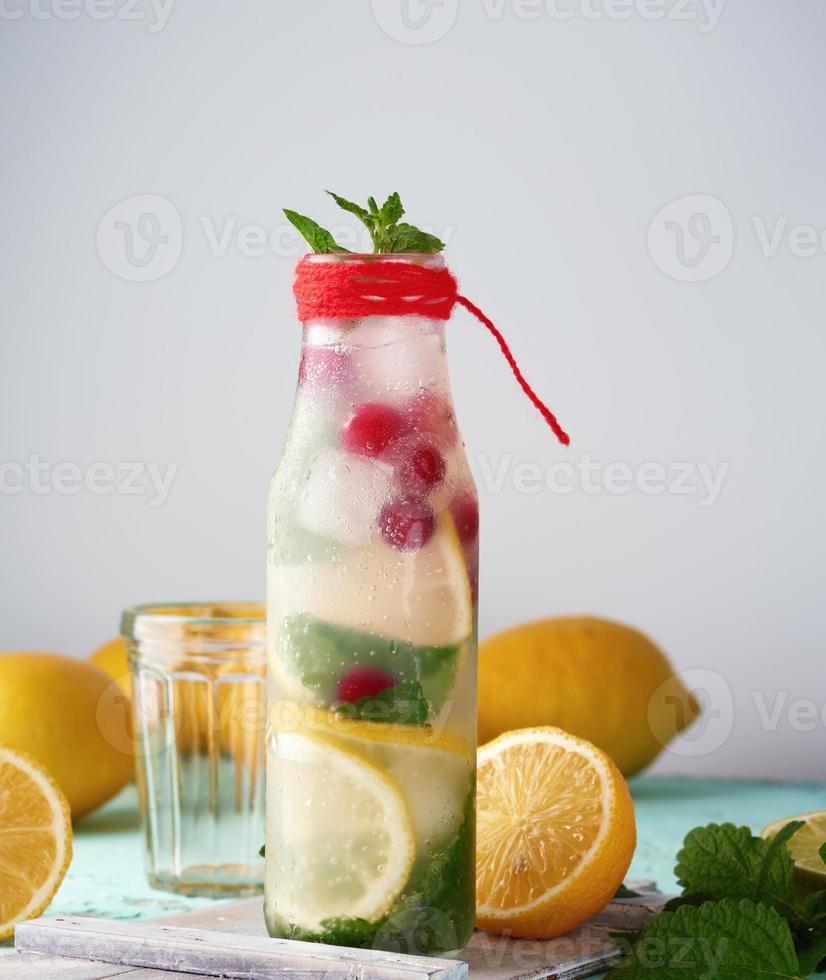 summer refreshing drink lemonade with lemons, cranberry, mint leaves, lime in a glass bottle photo