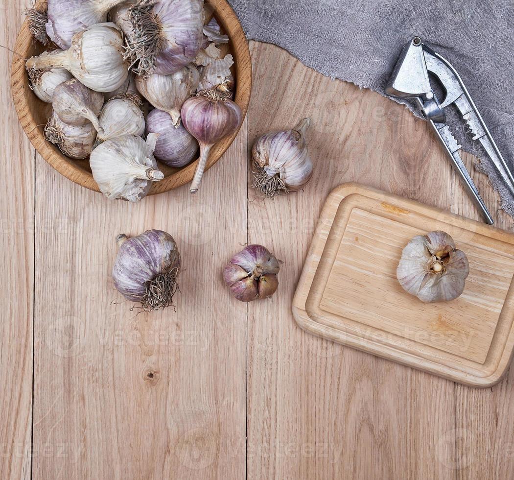 unpeeled fresh garlic fruits in wooden bowl photo