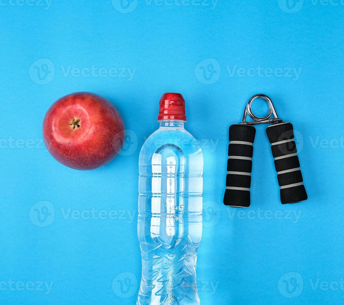 plastic water bottle, red ripe apple and sports expander photo