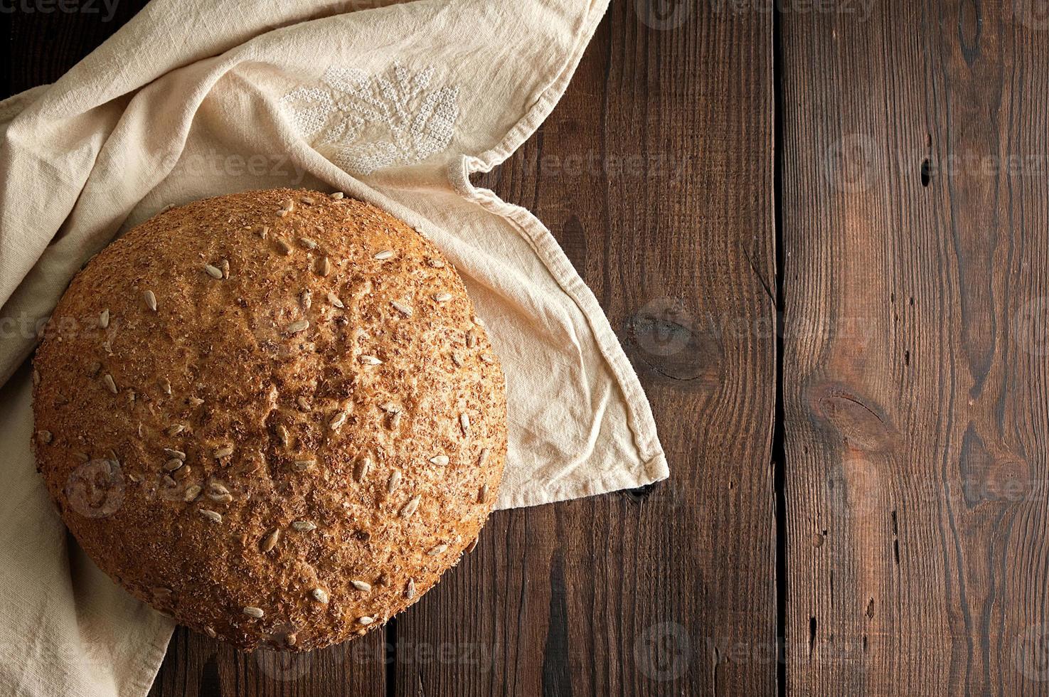 baked round rye bread with sunflower seeds on a beige textile napkin photo