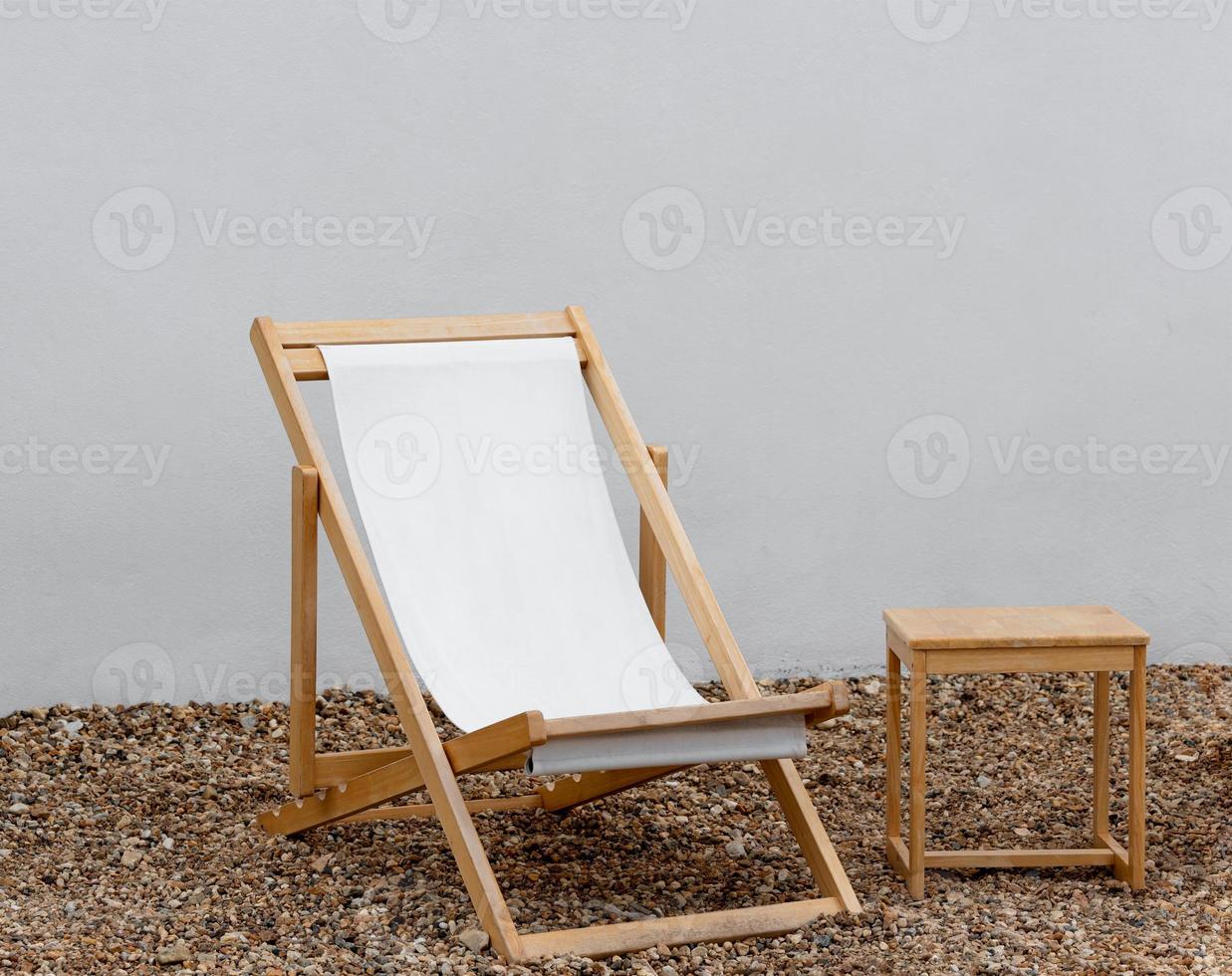 Beach chair on Pebble with White concrete wall background, Hammock chair with wooden table on white paint Cement backdrop,Vertical banner with copy space for text for Spring,Summer holidays concept photo