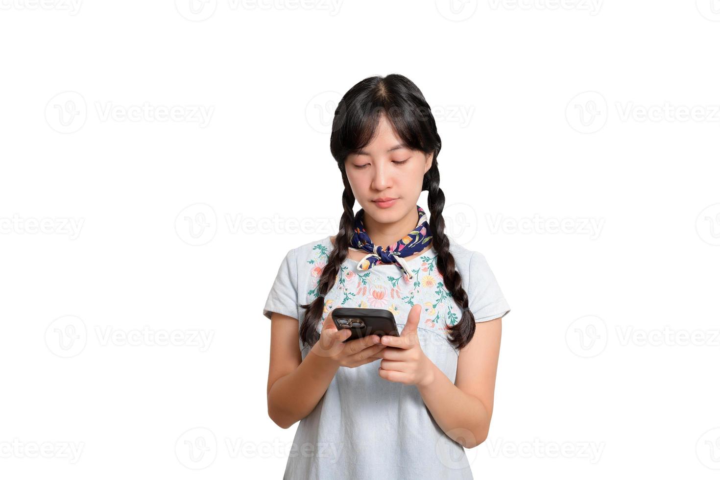 retrato de una feliz y hermosa joven asiática vestida de mezclilla usando un smartphone con fondo blanco. foto de estudio