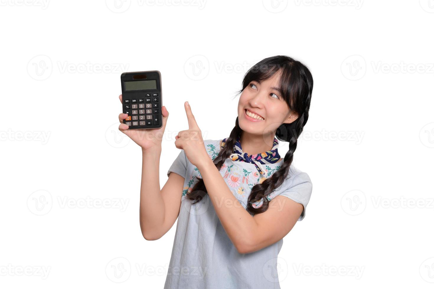 retrato de una hermosa joven asiática vestida de mezclilla sosteniendo una calculadora de fondo blanco. concepto de compras en línea de negocios. foto